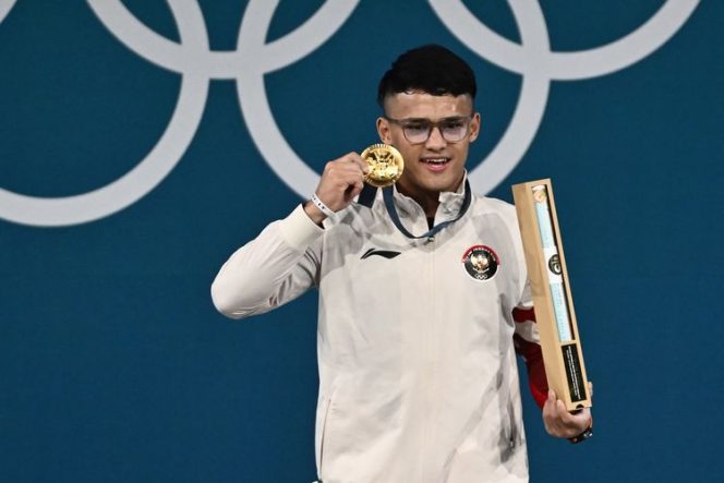 
					Rizki Juniansyah,memamerkan medali emas yang dia raih pada cabor angkat besi kelas 73 kg Olimpiade Paris 2024